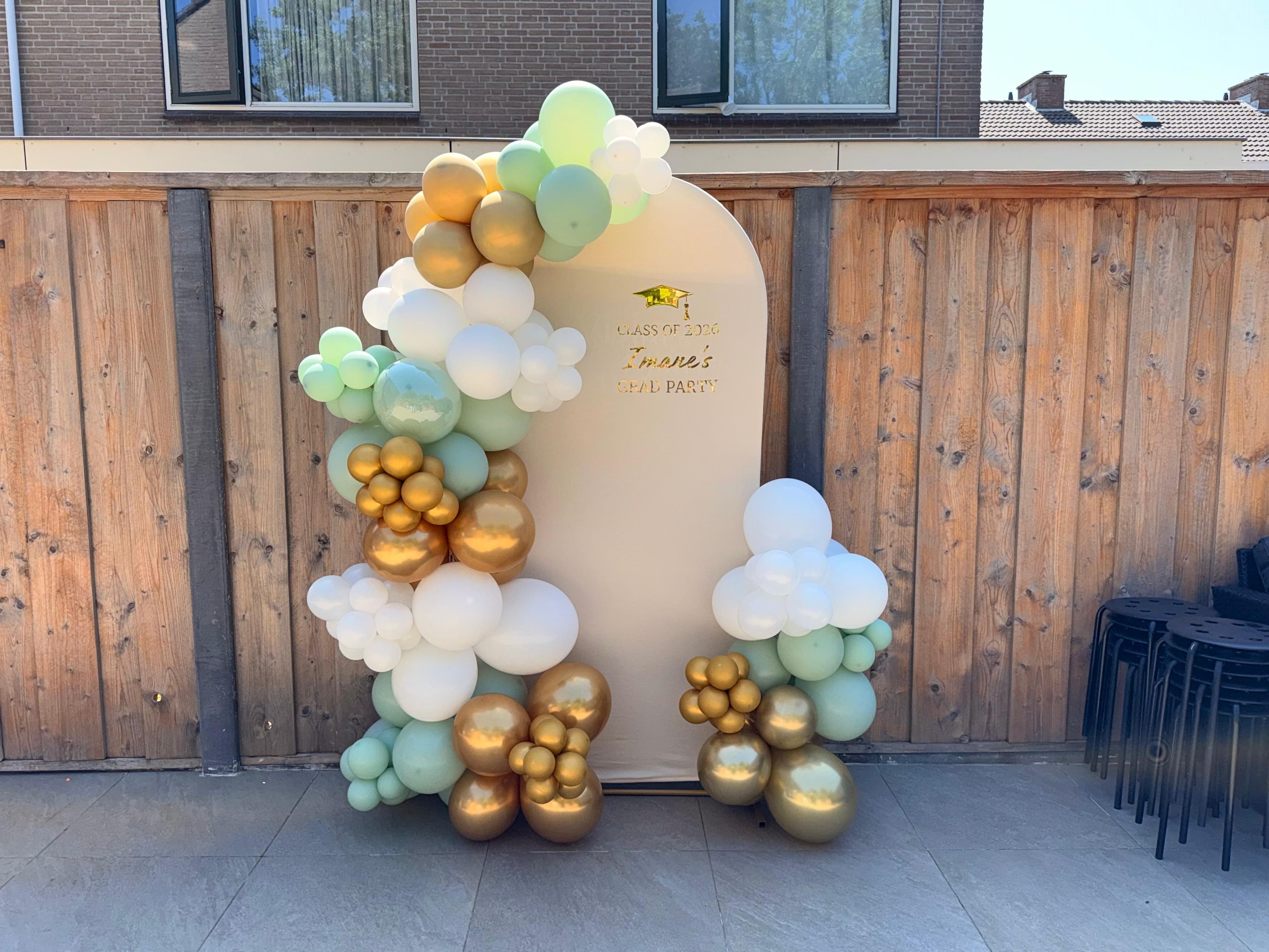 Groen-witte ballonnendecoratie met gouden accenten voor een afstudeerfeest