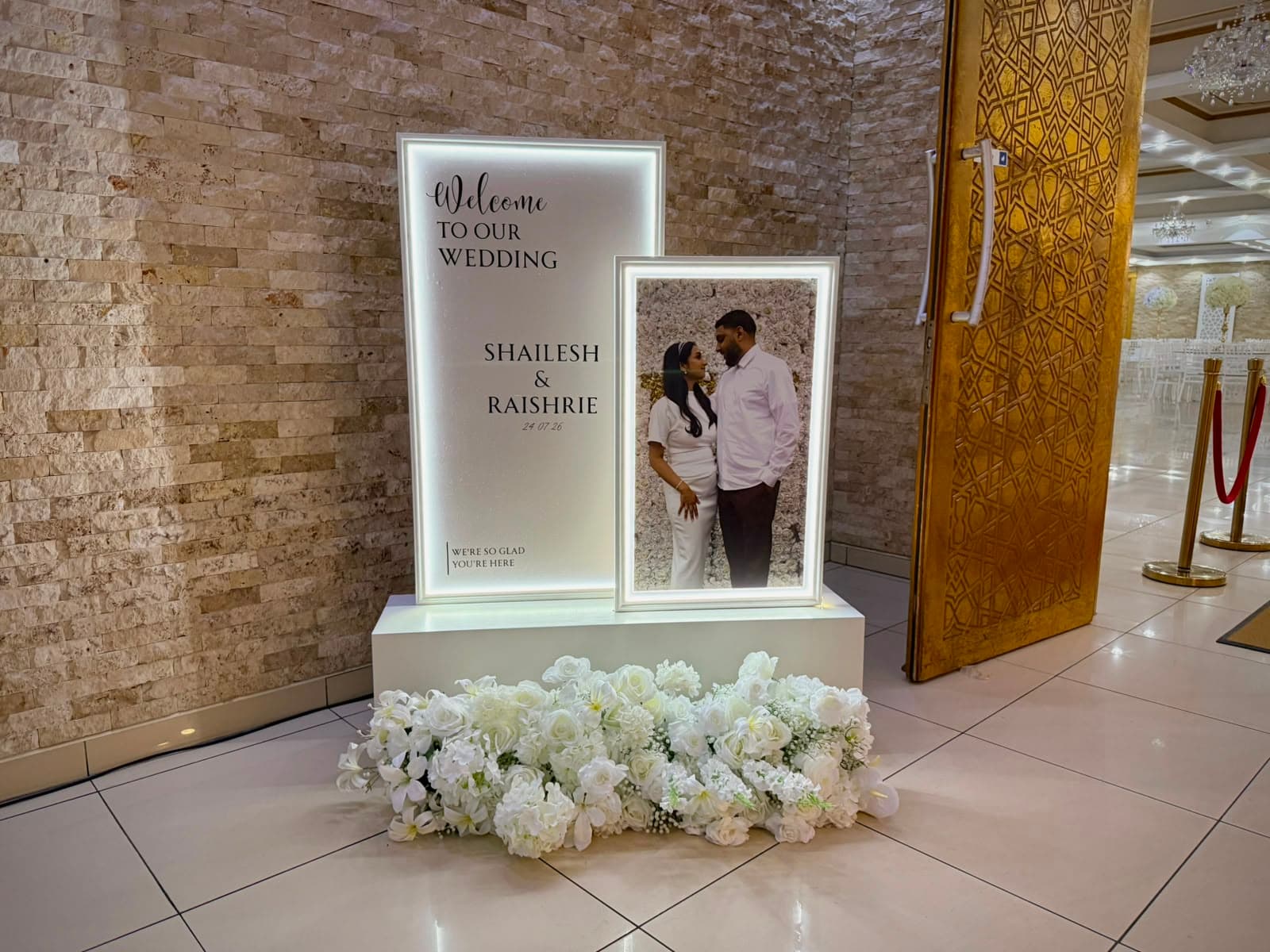 Verlicht welkomstbord met persoonlijke foto en witte bloemen